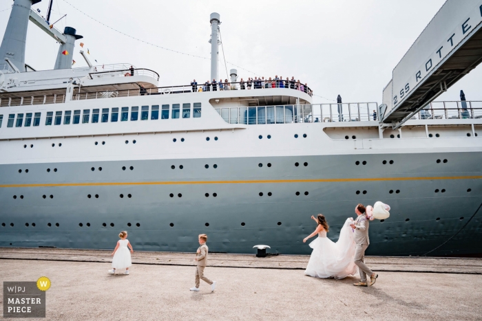 NL bride and groom walking past cruise ship Netherlands Wedding Photography - Image contains: bride, groom, flower girl, boy, cruise ship
