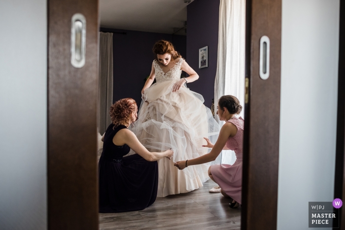 Fotografia de casamento na Bulgária da noiva recebendo ajuda com o vestido antes da cerimônia