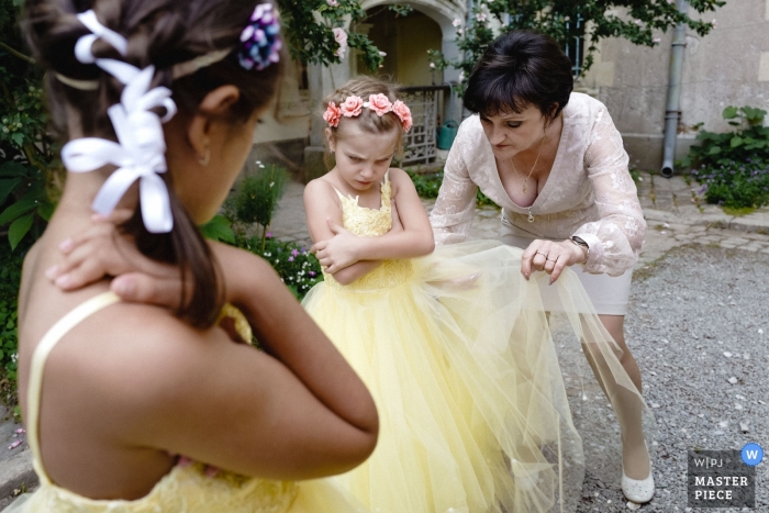 Photo by: <a href="https://www.wpja.com/contests/2019-v13/best-wedding-photographers/2550618">Jeremy Fiori - Angers </a> Wedding Photos from Chateau Allure du lac | The girl isn't happy her grand'ma adjusts her dress