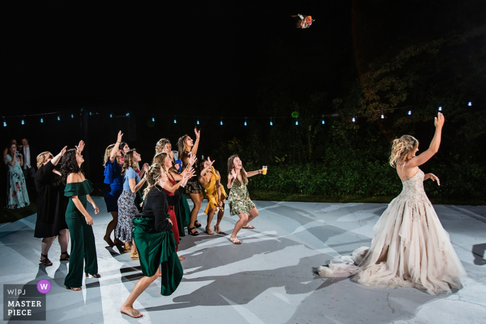 A noiva de Nova Jersey joga seu buquê na pista de dança durante a recepção do casamento