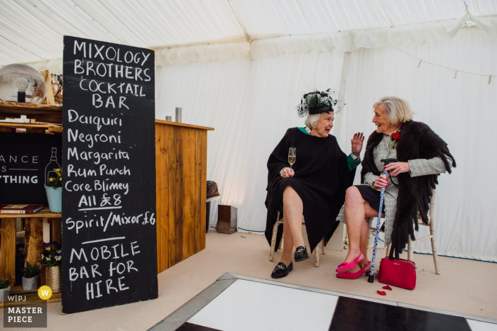 Private Farm in der Nähe von Ely, Großbritannien - Hochzeitsfotografie von zwei älteren Frauen, die in der Nähe der Bar etwas trinken