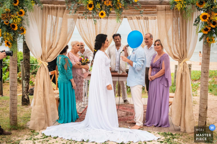 The blue-headed groom. Balloon during vows. Grumari Beach Garden - Rio de Janeiro - Brazil Outdoor Wedding Ceremony Photography | The blue-headed groom. Balloon during vows. Bride and Groom.