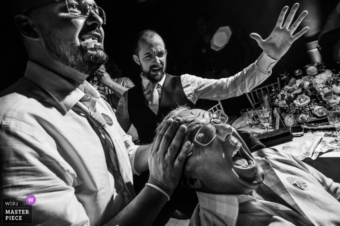 Fotografía de boda de Paulinia del hombre con la boca abierta a punto de recibir una bebida de sus amigos en la pista de baile