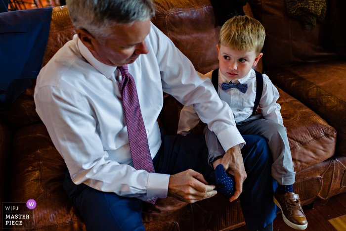Photo by: <a href="https://www.wpja.com/contests/2019-v13/best-wedding-photographers/2551494">Sarah V. Martinez - Dover New Hampshire</a> Bald Mountain Camps Rangeley Maine Wedding Venue Photography - The bride's son gets dressed with his grandfather at the Maine wedding ceremony