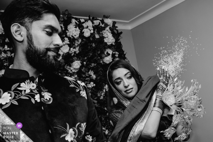 Photo by: <a href="https://www.wpja.com/contests/2019-v14/best-wedding-photographers/2552221">Rohit Gautam - Bedford Bedfordshire</a> United Kingdom wedding photo of the bride leaving her parents house and doing a ritual to throw rice. She is crying at the same time and unable to hide her emotions.