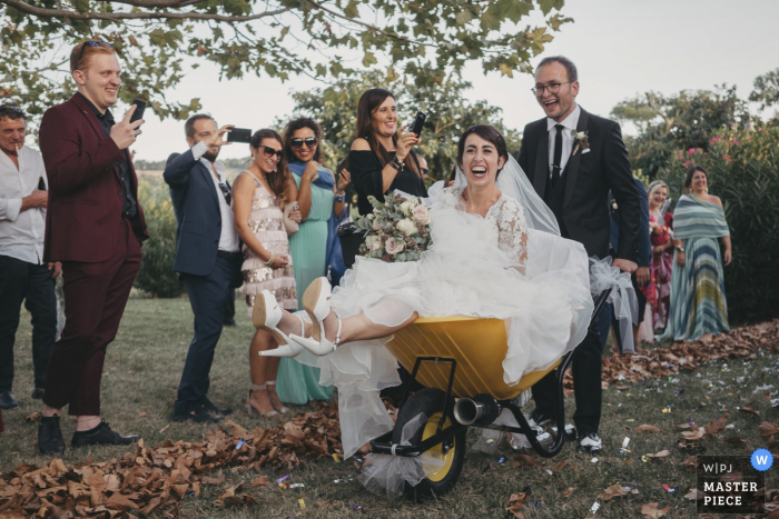 Photo by: <a href="https://www.wpja.com/contests/2019-v14/best-wedding-photographers/2552245">Sabrina Vinci - Civitanova Marche Macerata</a> San Girio alla Fonte wedding image of the bride taking a ride in a wheelbarrow after the ceremony.