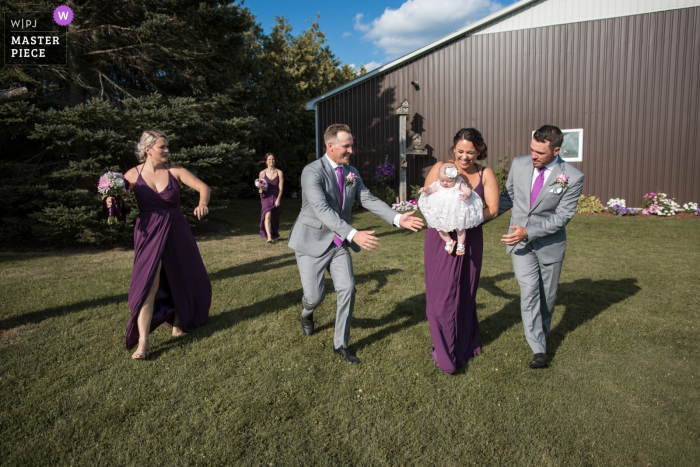 Photo by: <a href="https://www.wpja.com/contests/2019-v14/best-wedding-photographers/2552439">Lori-Anne Crewe - Ayr Ontario</a> London, Ontario wedding photographer: "Just after the ceremony, the wedding party was dashing away when the bridemaid holding the flower girl almost trips. The groomsmen were on cue reaching for the baby."