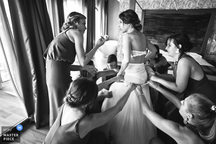 Photo by: <a href="https://www.wpja.com/contests/2019-v14/best-wedding-photographers/2552621">Franck Boutonnet - Lyon </a> The bride is putting her dress on with help of bridesmaids - Wedding photographer from Auvergne-RhĂ´ne-Alpes