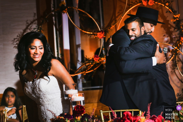 Photo by: <a href="https://www.wpja.com/contests/2019-v14/best-wedding-photographers/2552625">Franck Boutonnet - Lyon </a> Reception venue wedding photography in Auvergne-RhĂ´ne-Alpes - The groom is hugging his brother in law after he delivered his speech