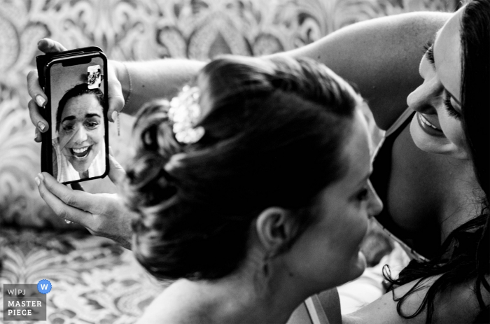 Foto di: <a href="https://www.wpja.com/contests/2019-v14/best-wedding-photographers/2554247"> James Nix - Charlotte North Carolina </a> Fotogiornalismo per matrimoni Hawthorne Hotel - La sposa mostra i suoi capelli attraverso FaceTime con un amico che non è riuscito a partecipare al matrimonio.