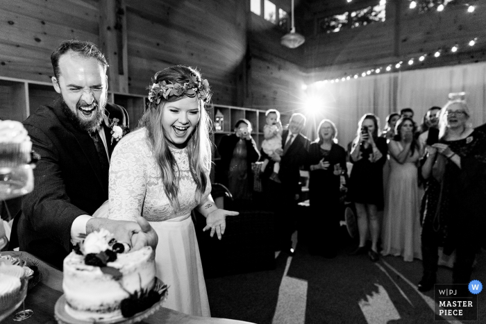 Photo by: <a href="https://www.wpja.com/contests/2019-v14/best-wedding-photographers/2554271">Kate Crabtree - Bangor Maine</a> Sugarloaf Mountain, Maine Wedding Venue Photographer - A bride and groom cut the cake with their hands at their Sugarloaf Mountain wedding in Maine.