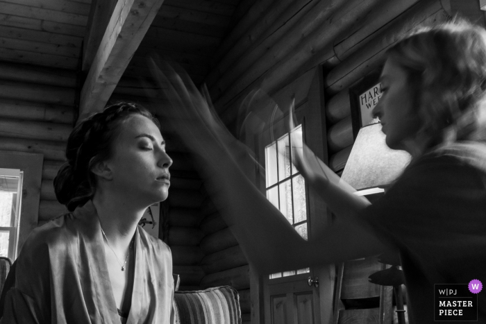 Photo by: <a href="https://www.wpja.com/contests/2019-v14/best-wedding-photographers/2554329">Brenda Bergreen - Evergreen Colorado</a> Colorado Wedding Photographer - Cabin at venue getting ready shots - Bride getting makeup done, drying the setting spray