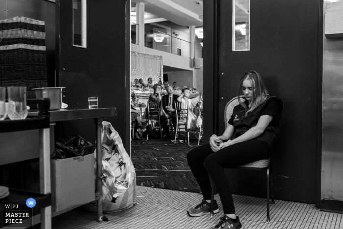 Waitress on her break during the wedding reception The Grand Imperial, Edmonton, AB, Canada Wedding Venue Photography - Waitress on her break during the wedding reception.