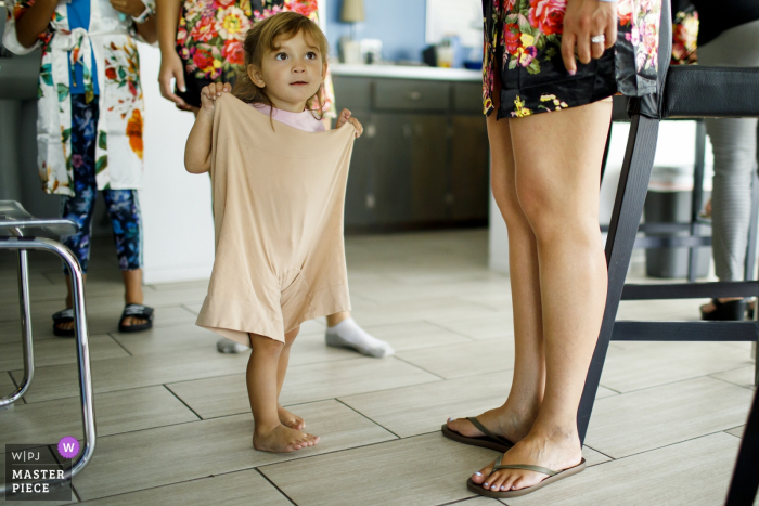 Foto door: <a href="https://www.wpja.com/contests/2019-v14/best-wedding-fotografen/2554362"> Justin Edmonds - Denver Colorado </a> Trouwfotograaf voor Denver, CO - De nicht van de bruid speelt verkleed met het nauwsluitende ondergoed van de bruid terwijl de dames zich klaarmaken op de trouwdag.
