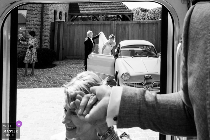 Wedding photographer for Antwerpen Flanders — bride getting out of the car with help