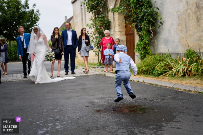 Foto von: <a href="https://www.wpja.com/contests/2019-v15/best-wedding-photographers/2555306"> Julien Roman - Paris </a> Hochzeitstagfotografie von der Île-de-France - Kirchenkind der Braut, die in Wasser springt