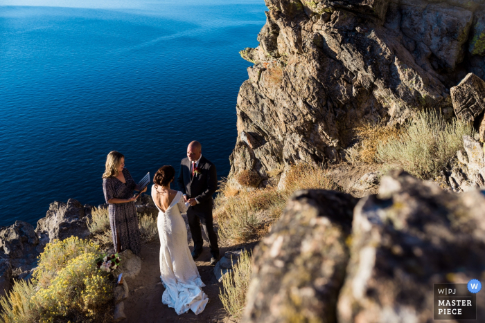 Photo by: <a href="https://www.wpja.com/contests/2019-v15/best-wedding-photographers/2555987">Lauren Lindley - South Lake Tahoe California</a> A couple elopes at the top of Cave Rock overlooking Lake Tahoe in Glenbrook, NV