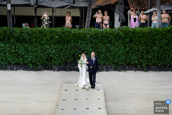 the bride enters the beach wedding ceremony with her father Wedding venue photographer: annli hotel Koh Samui Thailand — The bride enters with her father