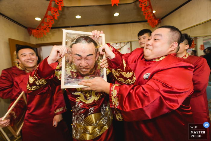 Fujian wedding image of the groom games - pushing his head through a frame wrapped in cellophane.