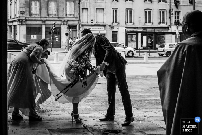 Photo by: <a href="https://www.wpja.com/contests/2019-v15/best-wedding-photographers/2556845">Coralie Castillo - Vernaison </a> Auvergne-Rhône-Alpes wedding day photo of the bride's dress being arranged before entering the church for the wedding ceremony.