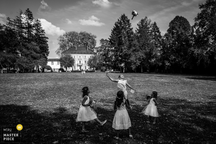 Photo by: <a href="https://www.wpja.com/contests/2019-v15/best-wedding-photographers/2556851">Coralie Castillo - Vernaison </a> France wedding image of four little girls throwing the bouquet into the air during play at the reception.