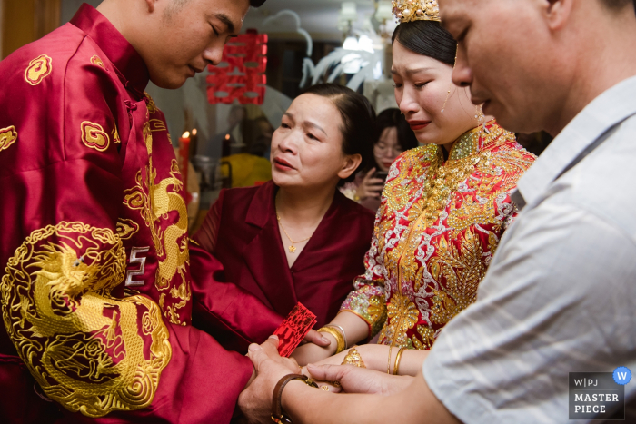 Foto: <a href="https://www.wpja.com/contests/2019-v15/best-wedding-photographers/2557002"> Kai Xiao - Sanming </a> China-Hochzeitsfoto des Braut- und Bräutigamhändchenhaltens mit Mutter und Vater für einen emotionalen Moment.