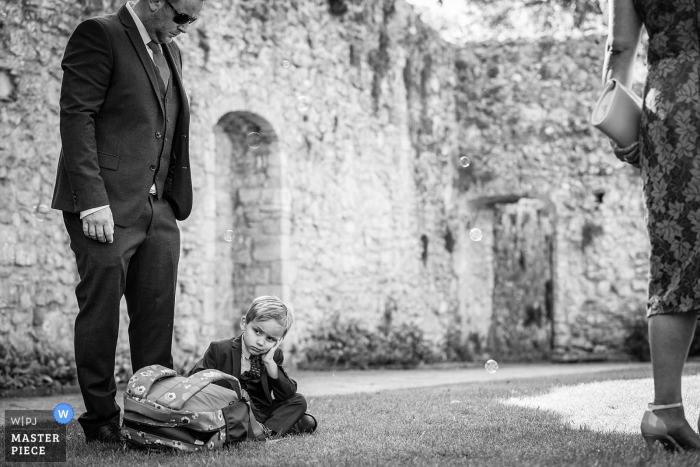 Beaulieu Abbey, Hampshire photo de mariage d'un jeune garçon avec sa tête dans ses mains aux pieds de son père. Le regard d'ennui sur son visage, mais il a peut-être été discipliné.