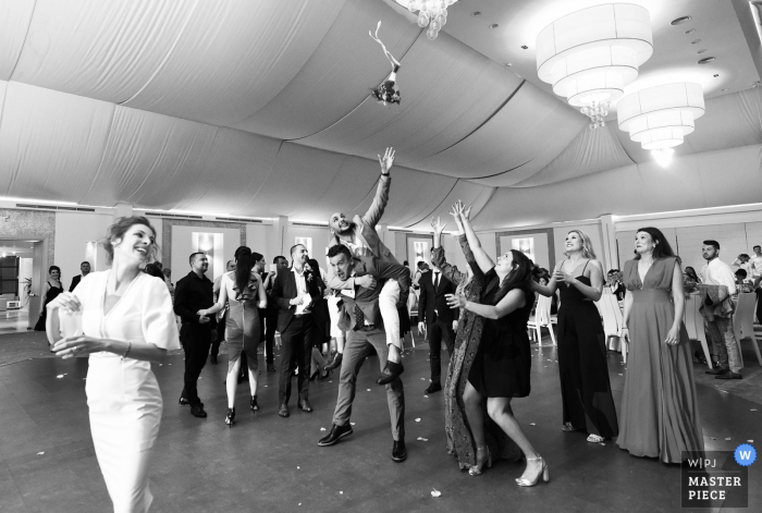 Image de mariage en Roumanie en noir et blanc de la mariée jetant le bouquet à ses invités.