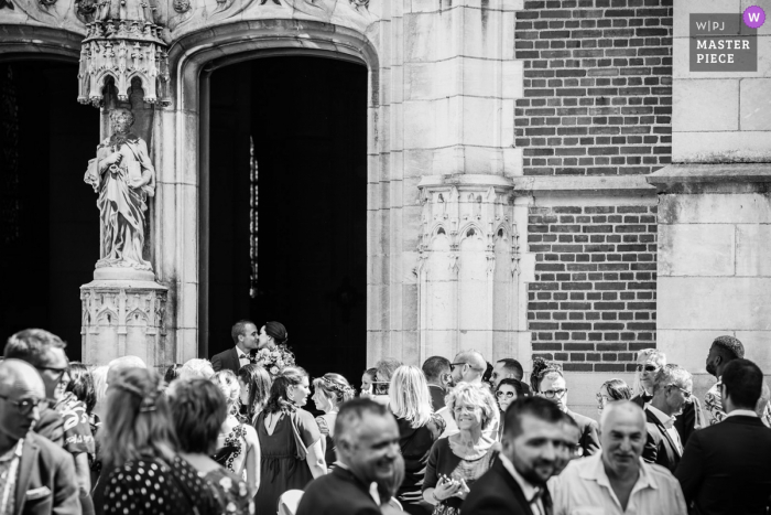 Photo by: <a href="https://www.wpja.com/contests/2019-v15/best-wedding-photographers/2557088">Kathleen Viron-Dunn - Macon </a> France wedding photography at the Church — Stolen kiss outside with the guests