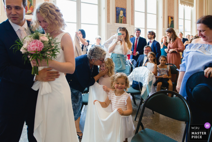 Photo by: <a href="https://www.wpja.com/contests/2019-v15/best-wedding-photographers/2557470">Lea Torrieri - Paris </a> During ceremony, the flower girl gets a kiss behind the bride and groom — Paris wedding photographer