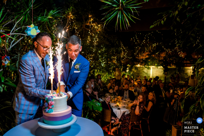 Michael's Restaurant, Santa Monica CA wedding venue photos — grooms cut into their firecracker topped unicorn wedding cake