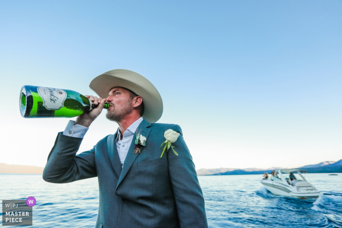 Foto: <a href="https://www.wpja.com/contests/2019-v15/best-wedding-photographers/2557559"> Nicky Byrnes - Carnelian Bay, Kalifornien </a> South Lake Tahoe, CA Hochzeitsfotograf - Der Bräutigam genießt nach seiner Zeremonie auf einem Boot mitten in Lake Tahoe nur einen kleinen Schluck Champagner.