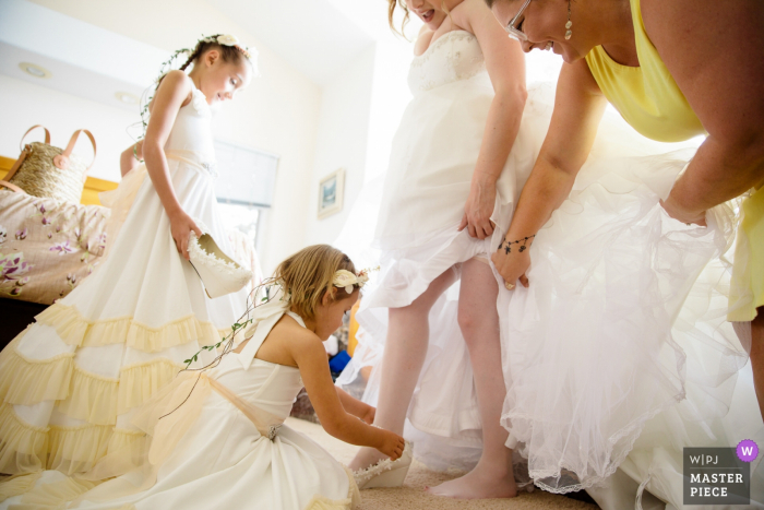 The bride gets help with her shoes from her flower girls and maid of honor South Lake Tahoe wedding photographer | The bride gets help with her shoes from her flower girls and maid of honor.