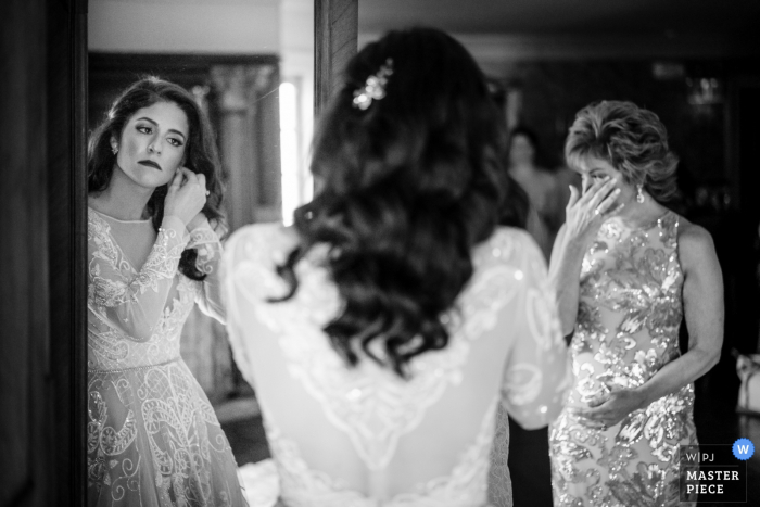 Foto von: <a href="https://www.wpja.com/contests/2019-v16/best-wedding-photographers/2562071"> JD Land - Marlton New Jersey </a> Empfangsort Fotografin für NJ - Bride, die den letzten Schliff gibt, als sie kurz vor der Zeremonie steht. Währenddessen schaut ihre Mutter zu und wird emotional.