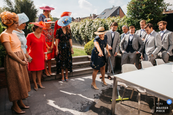 Foto von: <a href="https://www.wpja.com/contests/2019-v16/best-wedding-photographers/2562182"> Fille Roelants - Antwerpen Antwerpen </a> Hochzeitsfotografie der Mutter des Brauthauses - die Schwester der Braut gibt einem Trauzeugen Anweisungen zum Trocknen des Bodens für die ankommende Braut