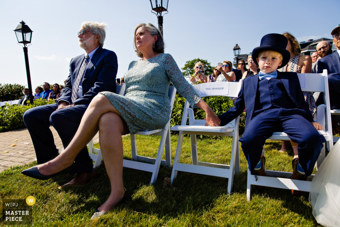 Photo by: <a href="https://www.wpja.com/contests/2019-v16/best-wedding-photographers/2562216">Kate Crabtree - Bangor Maine</a> French's Point, Stockton Springs Maine wedding photography - A ring bearer and parents of the bride watch the wedding ceremony