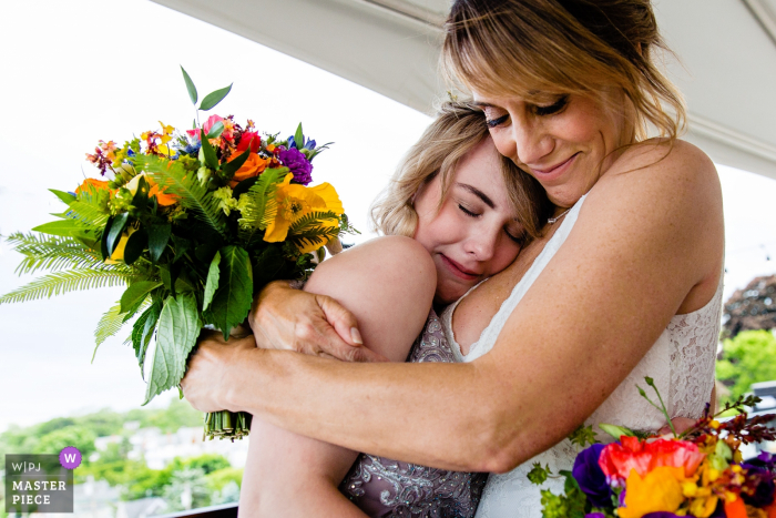 Photo by: <a href="https://www.wpja.com/contests/2019-v16/best-wedding-photographers/2562222">Kate Crabtree - Bangor Maine</a> Camden, Maine wedding photography | A bride hugs her daughter after her wedding ceremony