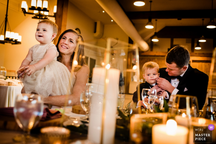 Foto: <a href="https://www.wpja.com/contests/2019-v16/best-wedding-photographers/2562265"> Jacob Hannah - Lincoln Vermont </a> Sugarbush Resort - Hochzeitsfotografie in Warren, VT | Braut und Bräutigam hören sich Toasts an und essen mit ihren beiden Kindern zu Abend