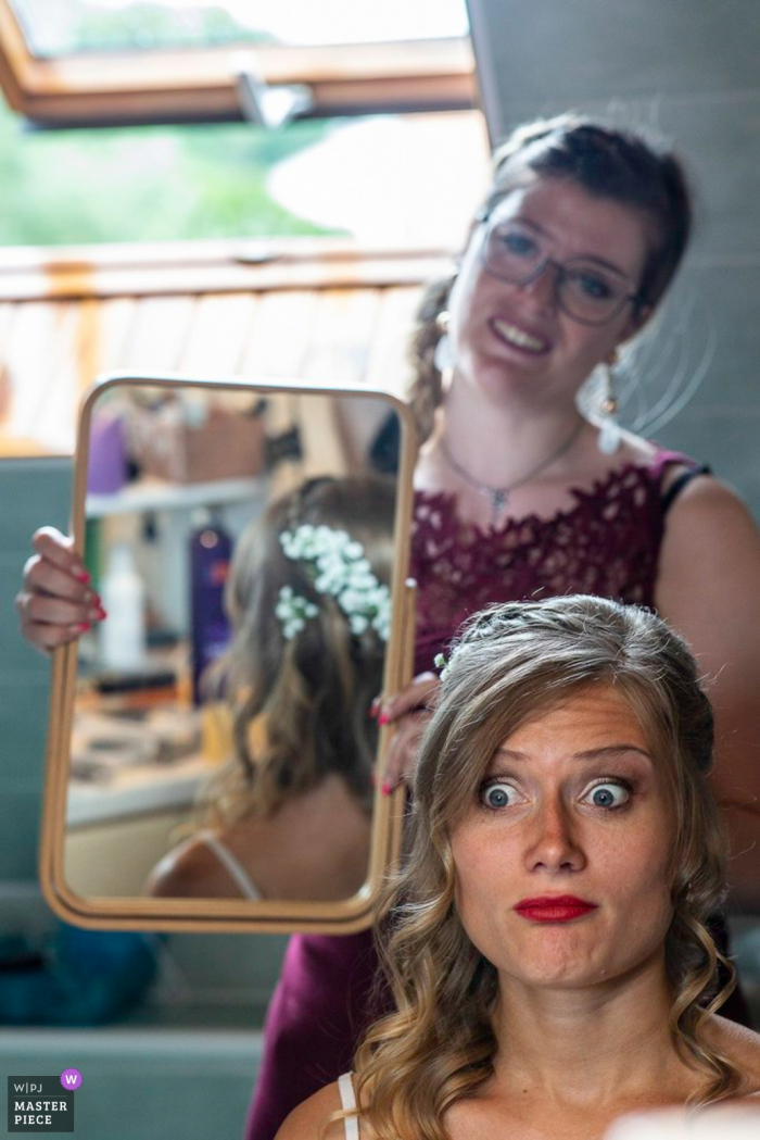 Lièpvre se prépare pour la photographie de mariage - La mariée vérifie ses cheveux dans un miroir vertical.