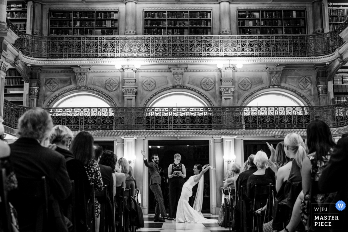 Photo by: <a href="https://www.wpja.com/contests/2019-v17/best-wedding-photographers/2563046">Kathleen Ricker - Linthicum Heights Maryland</a> Peabody Library - Baltimore MD wedding ceremony pictures of the bride and groom celebrating with arms up in the air.