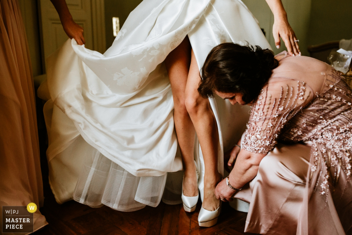 Imagens do casamento no local Château Tourreau - noiva recebendo ajuda com seus sapatos