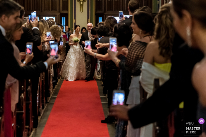 Photo by: <a href="https://www.wpja.com/contests/2019-v17/best-wedding-photographers/2564119">Isabelle Hattink - Rotterdam Zuid Holland</a> Amsterdam - Krijtbergkerk wedding reportage | Bride with father walking in the church to lots of cameras at the wedding