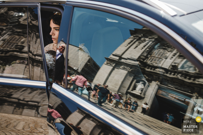 Photo by: <a href="https://www.wpja.com/contests/2019-v17/best-wedding-photographers/2564268">Daniel Monteiro - Porto </a> menino conhece menina - portugal wedding photography showing the bride getting out of the car with the church reflections in the auto glass
