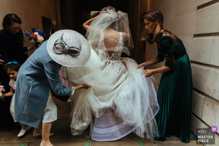 Photo by: <a href="https://www.wpja.com/contests/2019-v17/best-wedding-photographers/2564354">Lyndsey Goddard - London London</a> St Bride's Church, London wedding pictures | Bridesmaid adjusting the bride's dress