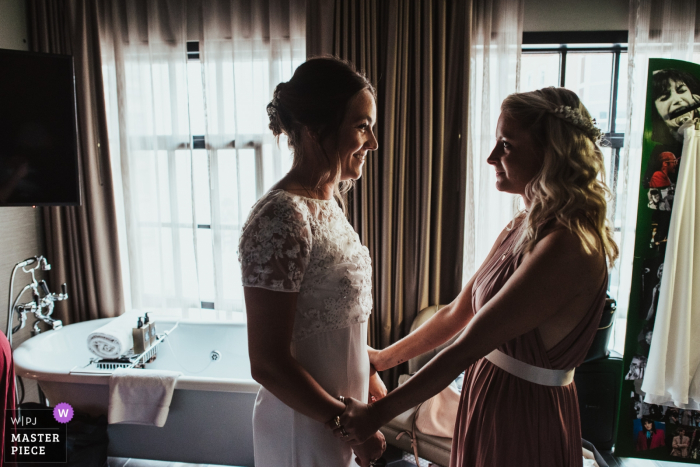 The Curtain Hotel, Hackney, Londra - foto delle location per matrimoni - Una sposa è rassicurata dalla sua damigella prima della cerimonia di nozze