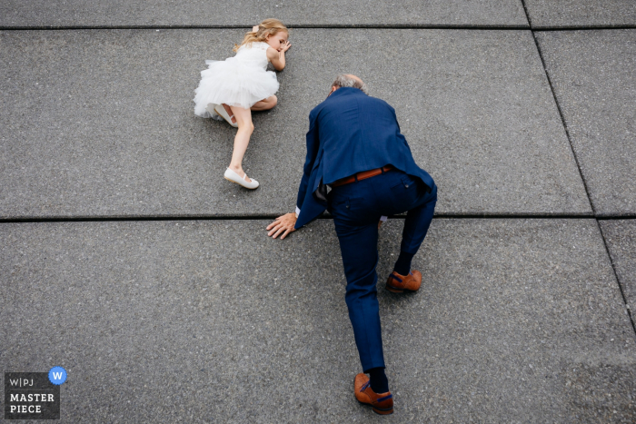 Photo by: <a href="https://www.wpja.com/contests/2019-v17/best-wedding-photographers/2564614">Leonard Walpot - Utrecht Utrecht</a> Outside the venue wedding photography, Hotel New York, Rotterdam, Netherlands - Daughter of the bride and groom and her granddad are climbing a wall.