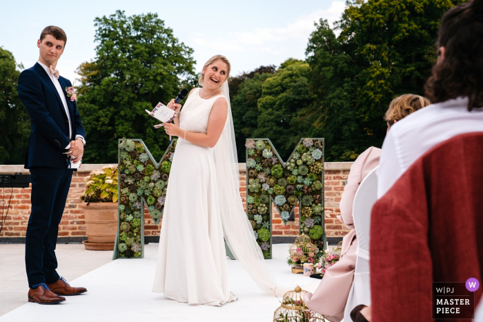 Photo by: <a href="https://www.wpja.com/contests/2019-v17/best-wedding-photographers/2564775">Yves Schepers - Bonheiden Antwerpen</a> Ceremony Wedding Reportage Photography - Bride makes a joke about the groom and they look for confirmation in the audience