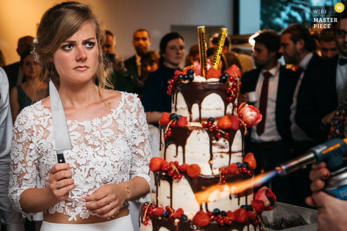 Photo by: <a href="https://www.wpja.com/contests/2019-v17/best-wedding-photographers/2564795">Fille Roelants - Antwerpen Antwerpen</a> Flanders wedding photographer: Reception venue photos showing the bride is contemplating the cake cutting right after it was taken in to the venue