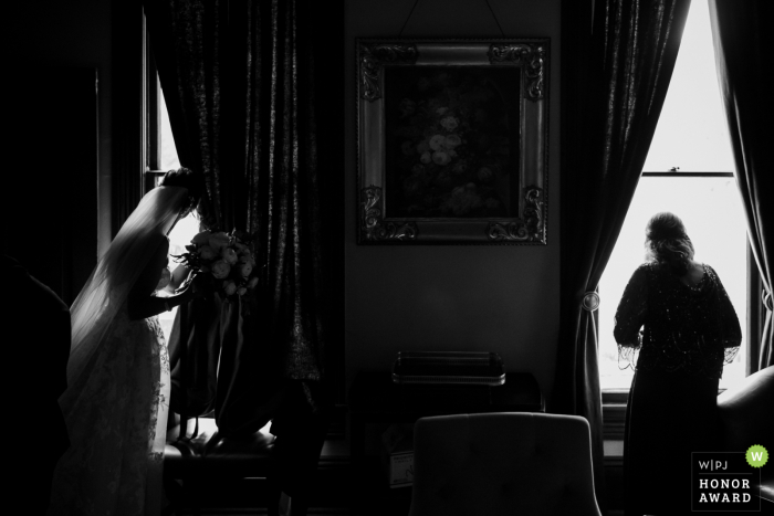 Barr Mansion, Austin, Texas wedding venue photo: Bride and mother looks out of windows as wedding procession starts 