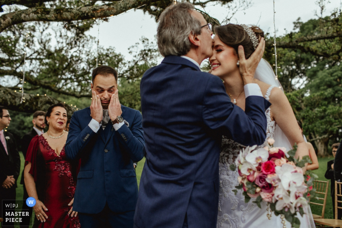 Noivo emocionado ao ver o pai da noiva beijando-a na cerimônia - Alto da Capela